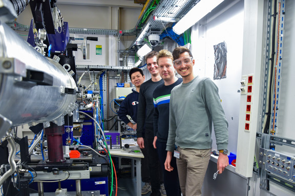 Groepsfoto van drie onderzoekers bij hun apparatuur.