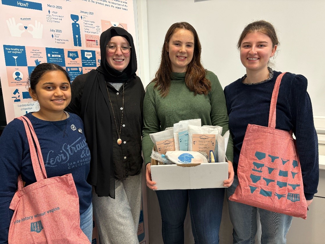 Een groep lachende mensen met boodschappentassen staat voor een achtergrond van informatieposters.