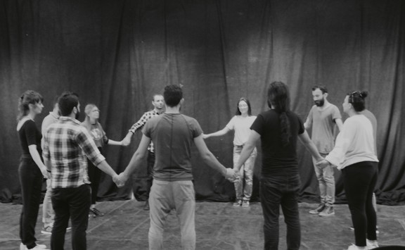 een groep van mensen die in een cirkel staat terwijl ze elkaar een hand geven