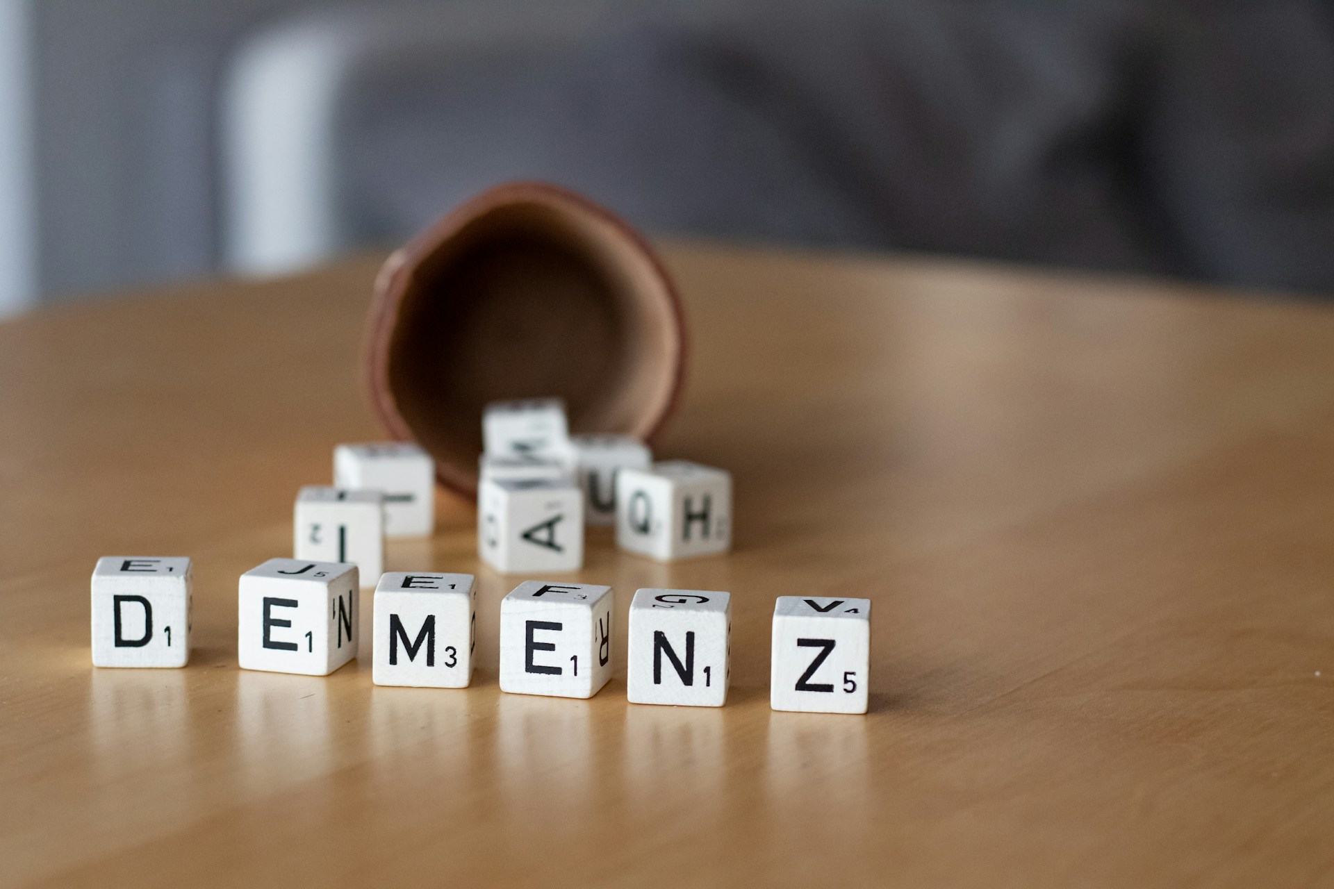 Witte blokken met letters op een houten tafel, die het woord 'Dementie' spellen.