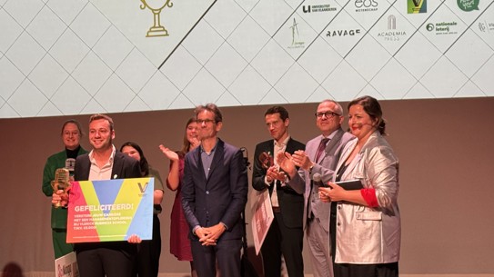 Foto van de winnaar van de Vlaamse PhD Cup met zijn trofee en cheque.
